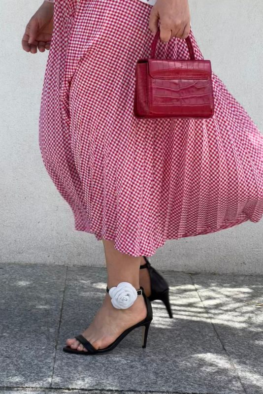 Invitada con falda de cuadros rosa y sandalias Camelia negras con flor blanca
