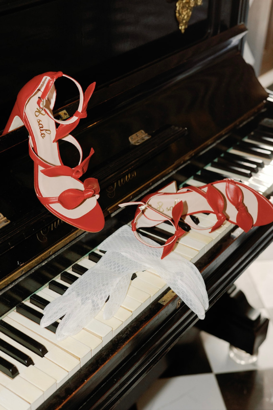 Sandalias París rojas con lazos sobre un piano