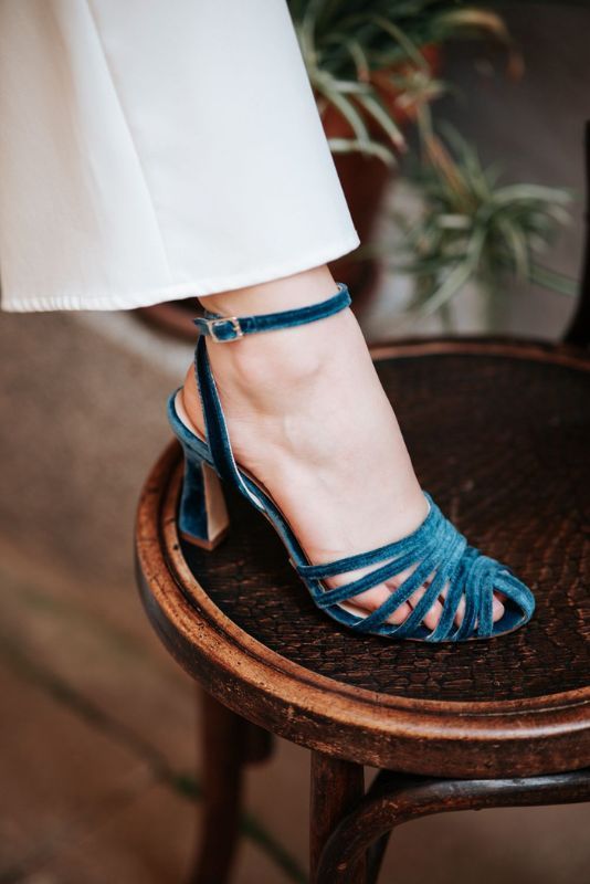 Sandalia Silvia en terciopelo azul petróleo sobre una silla de madera