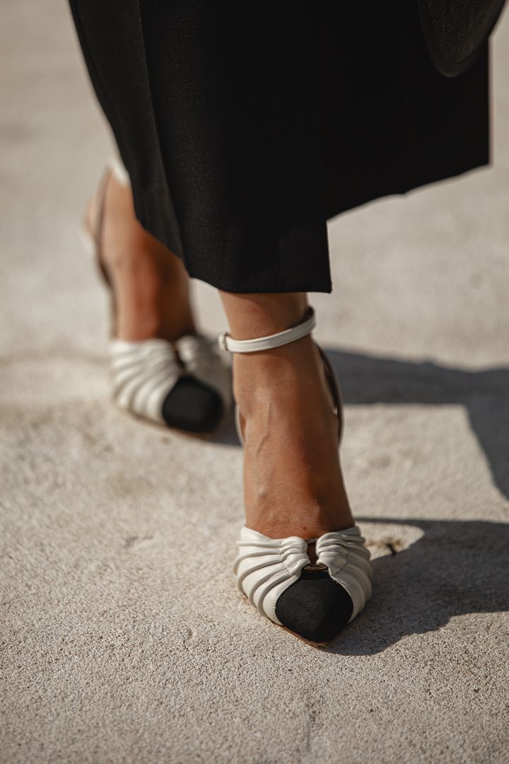 Zapatos destalonados Inés R en blanco con puntera negra, vistos de cerca